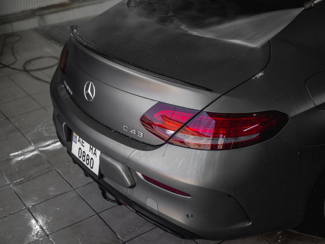 Close-up of a Mercedes Benz C43 coupe at a car wash, showcasing the elegant taillight.